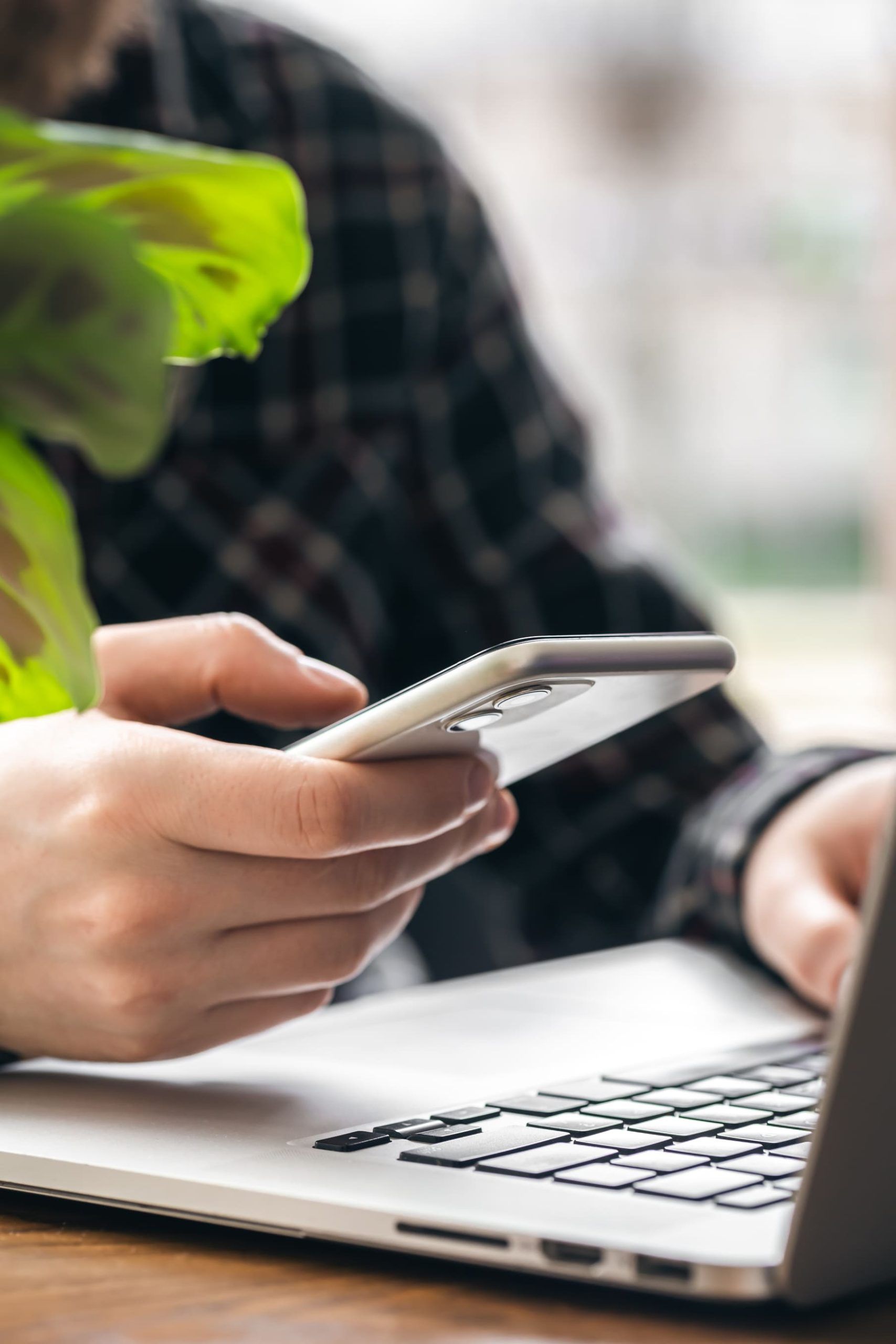 man holds smartphone works laptop 1 1 scaled